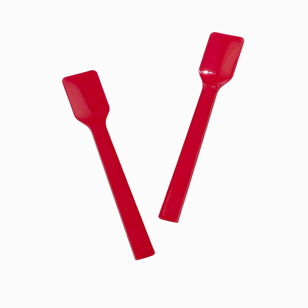 Two red plastic gelato spades in motion for serving high-volume desserts.