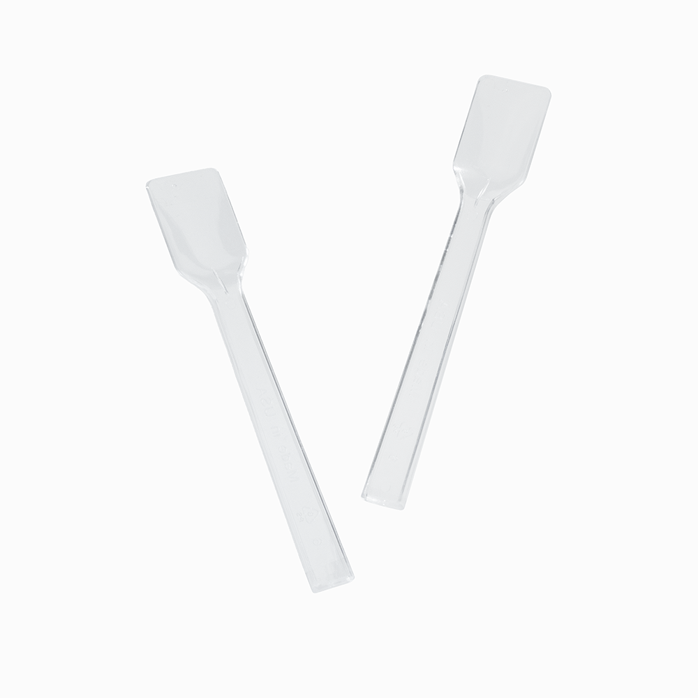 Two clear plastic gelato spoons angled for portioning authentic Italian ice.