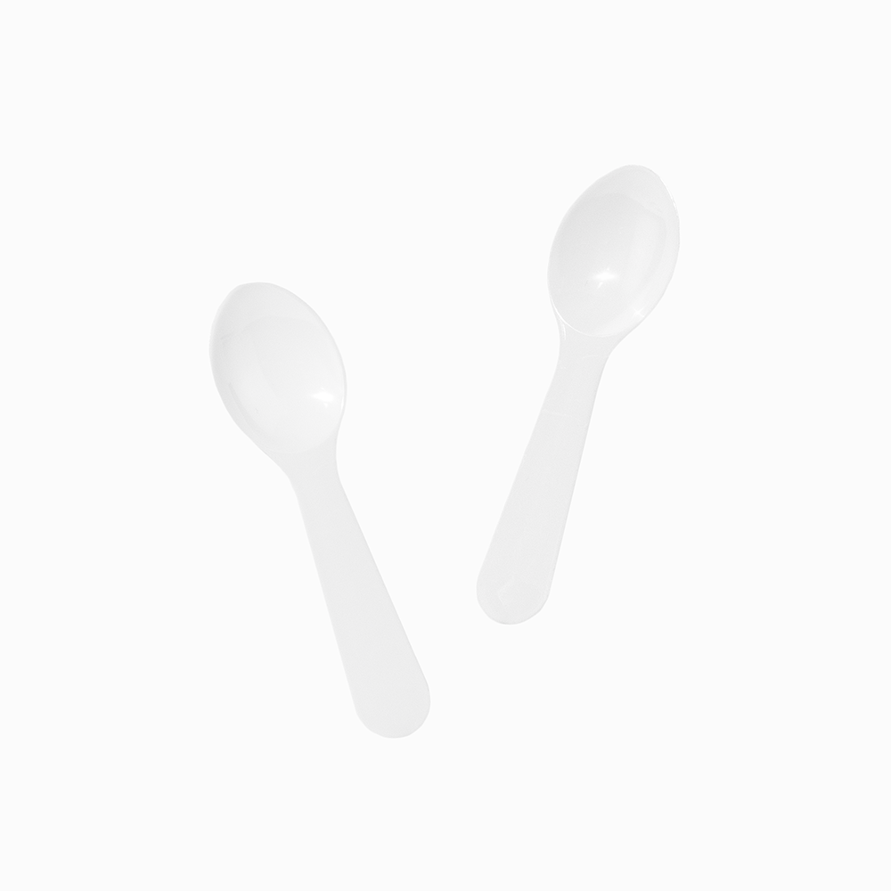 White disposable tasting spoons in motion for high-volume commercial food sampling.
