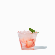 UNIQ 9 oz clear PET plastic cup showcasing a small iced beverage with fruit garnish, highlighting crystal-clear clarity for wholesale cocktails, samples, and cafe service.