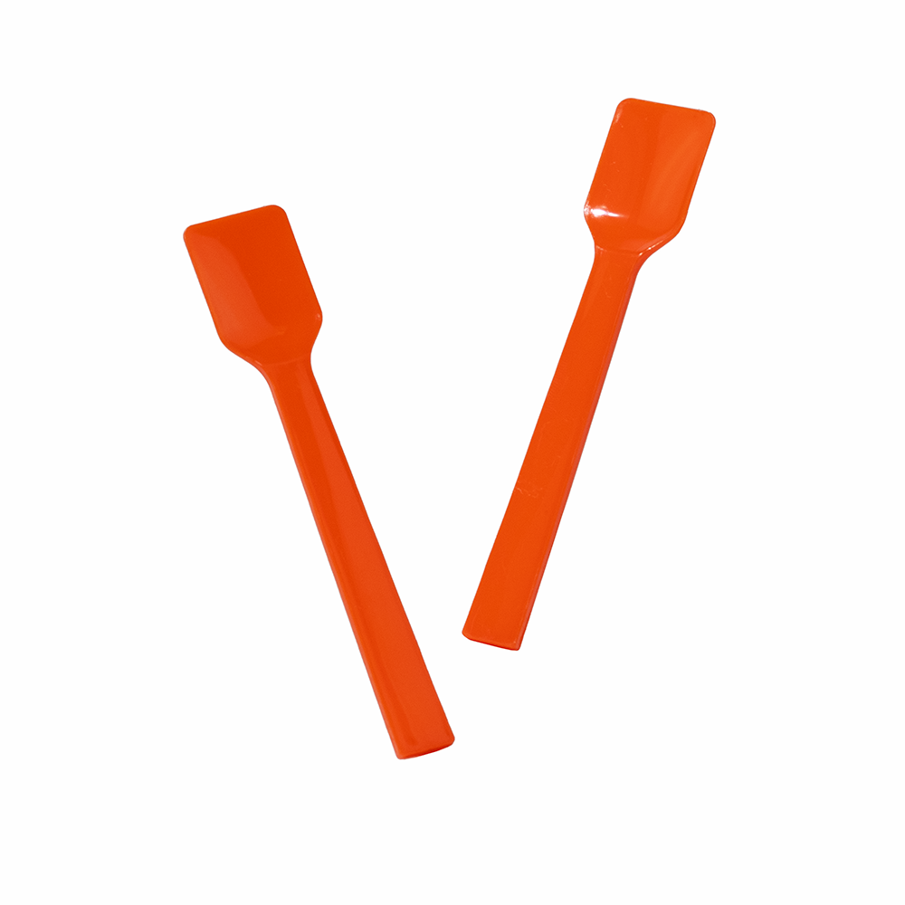 Two orange plastic gelato spoons angled for scooping and portioning sorbet.