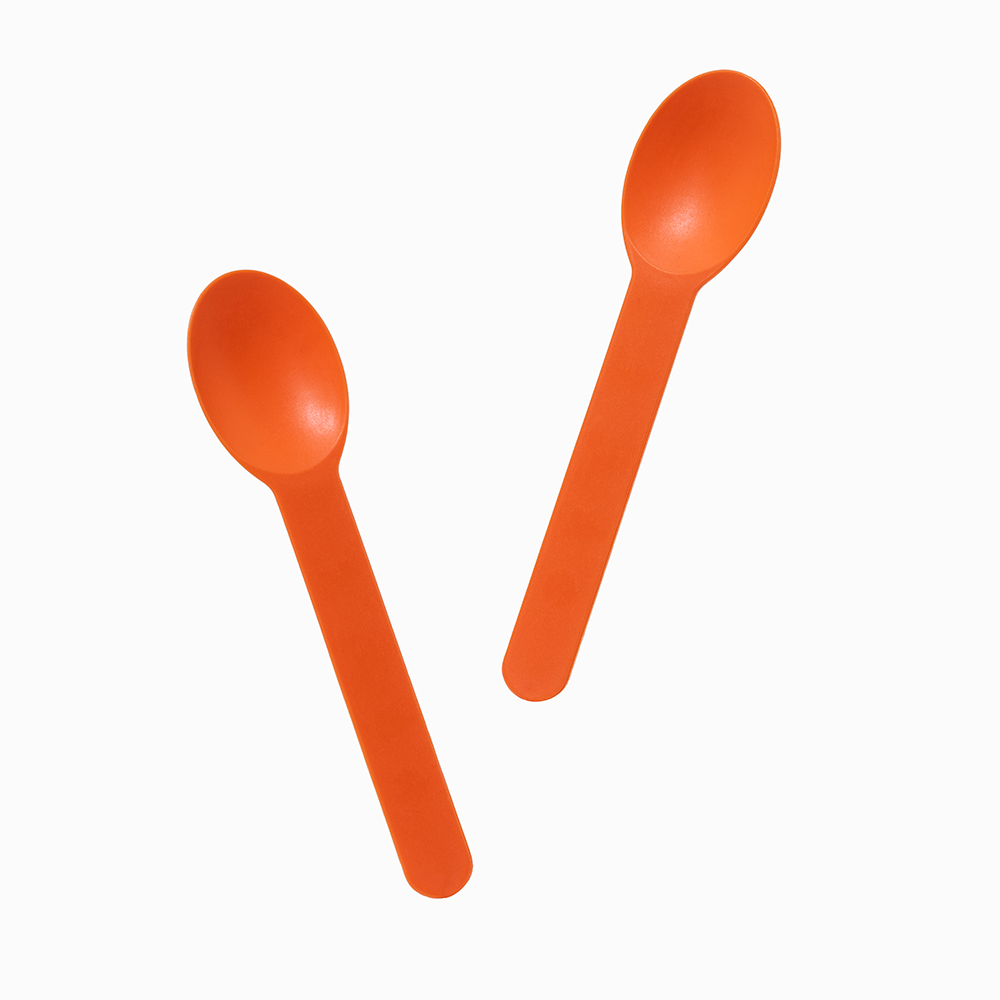 Orange rigid plastic dessert spoons angled for scooping thick artisanal gelato.