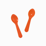 Orange disposable tasting spoons in motion for portioning sweet frozen treats.