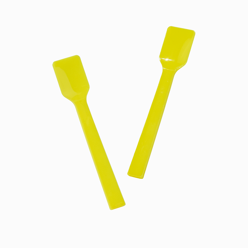 Two yellow plastic gelato spoons angled for serving sweet frozen treats.