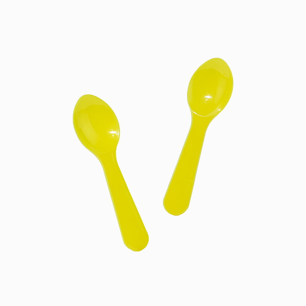 Yellow mini plastic tasting spoons arranged for serving dessert and food samples.